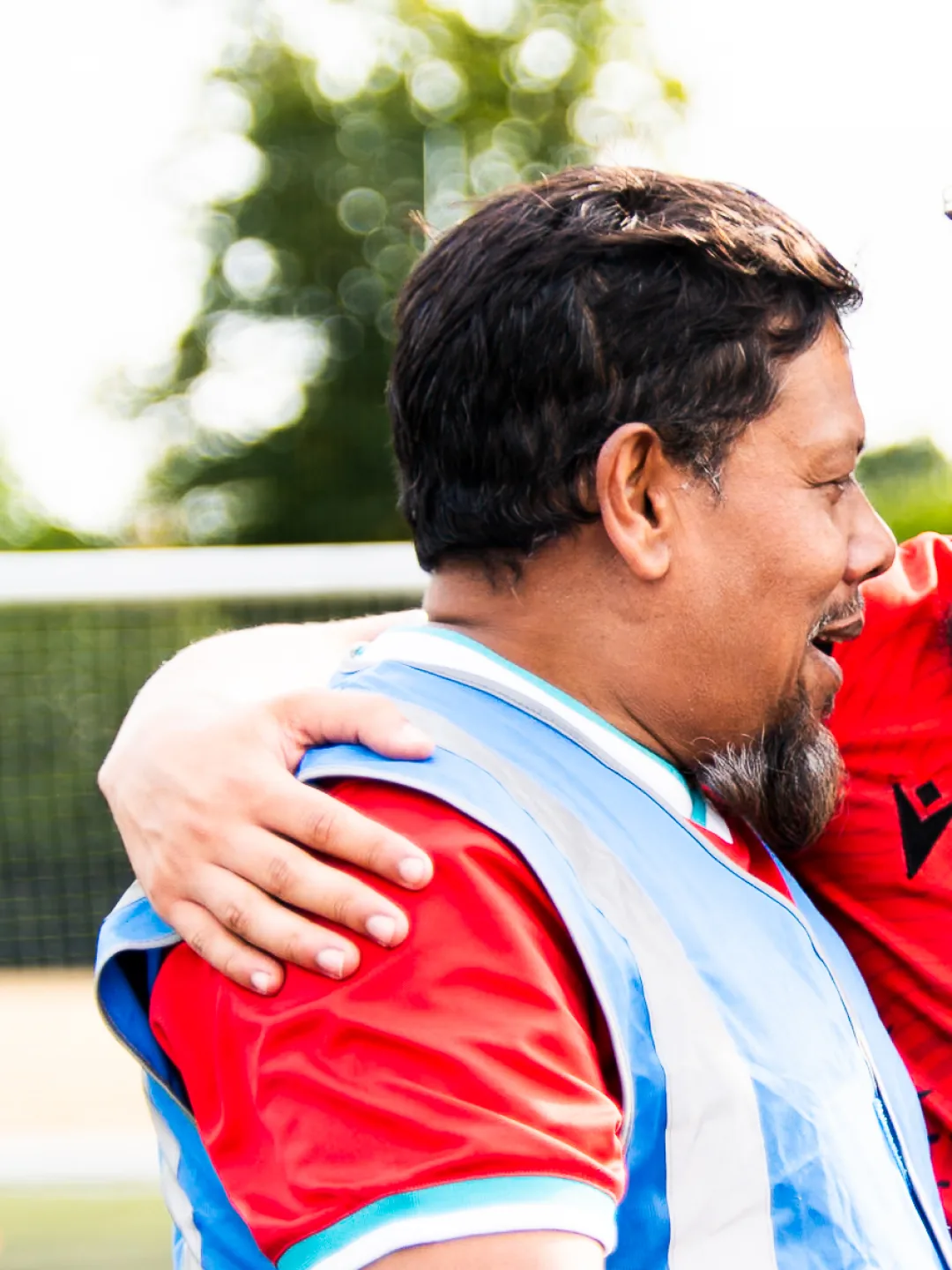 A player embracing a volunteer in a hi-vis vest