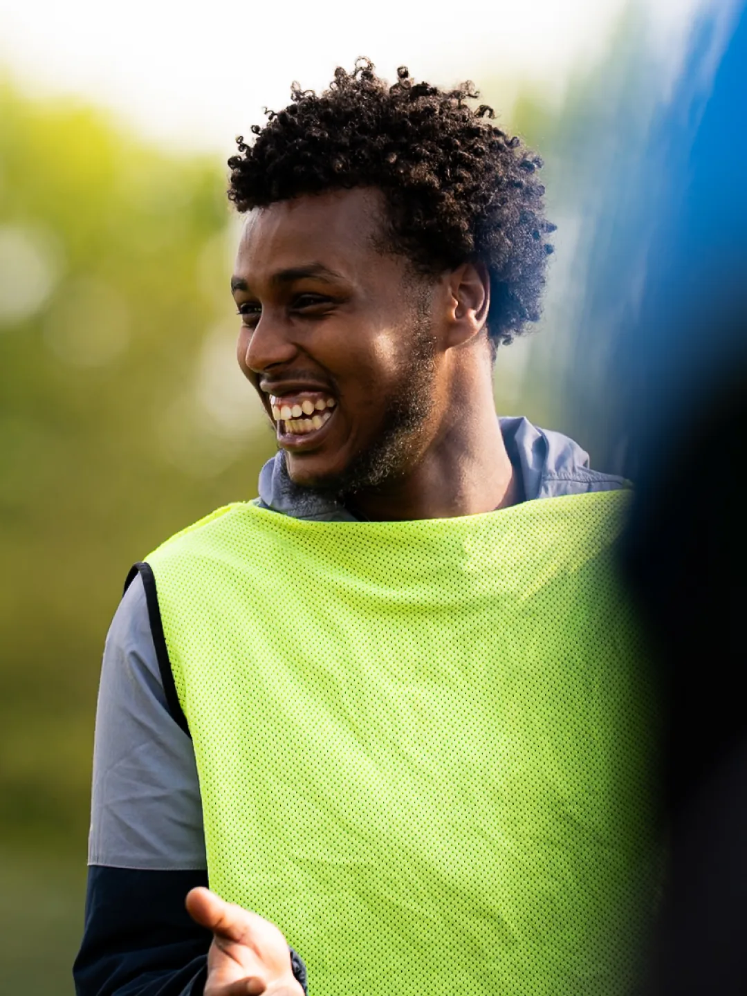 A player in a yellow bib, laughing