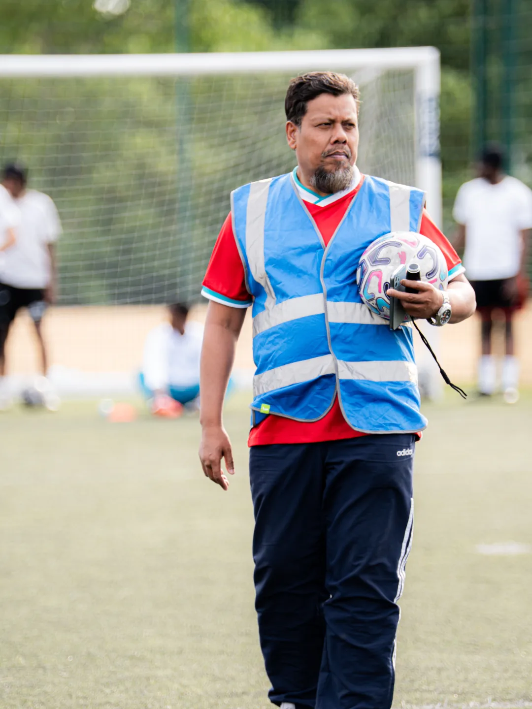 A volunteer in a blue hi-vis vest carrying the match ball